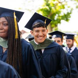 A group of people outside wearing academic regalia walking in a group