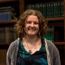 A woman smiling at the camera in front of bookshelves.