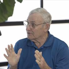 Man looking at a microphone with a plant in the background