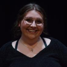 A woman smiling at the camera in front of black background