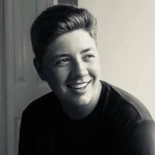 Black and white photo of a man smiling away from camera indoors