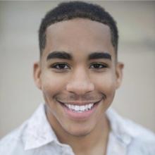 a man with black hair and a polo shirt outside