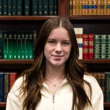 A woman smiling at the camera in front of bookshelves.