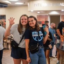 Two female students smiling at camera in school cafeteria