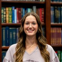 Girl standing in front of book case smiling at the camera