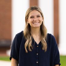 a woman stood outside with blond hair and a blue dress shirt