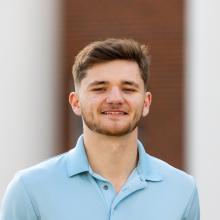 A photo of a man in a blue polo shirt standing outside