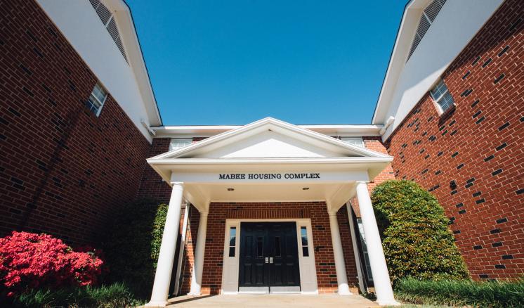 Entrance of a red brick building with white columns and a triangular pediment.