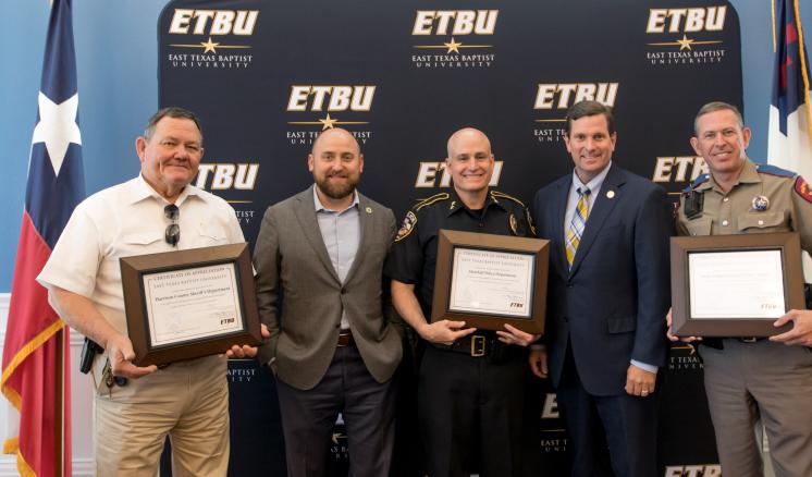 img_1 ETBU President J. Blair Blackburn and Vice President for Enrollment and Administrative Affairs Kevin Caffey present Harrison County Sheriff Tom McCool, Marshall Police Department Chief Cliff Carruth, and Texas Department of Public Safety Corporal Kevin Arnold during the annual Law Enforcement Appreciation Luncheon on May 14.