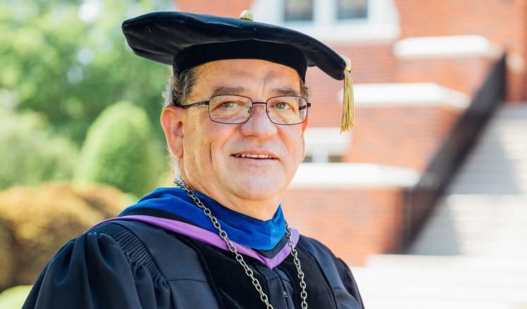 Dr. Warren Johnson outside in academic regalia