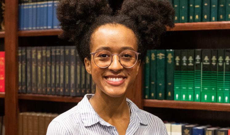 Person standing in front of a bookshelf filled with books.