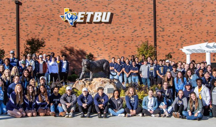 A large group of people in front of a red brick building with the "ETBU" logo.