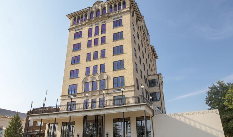 Tall beige building with multiple windows against a clear sky.