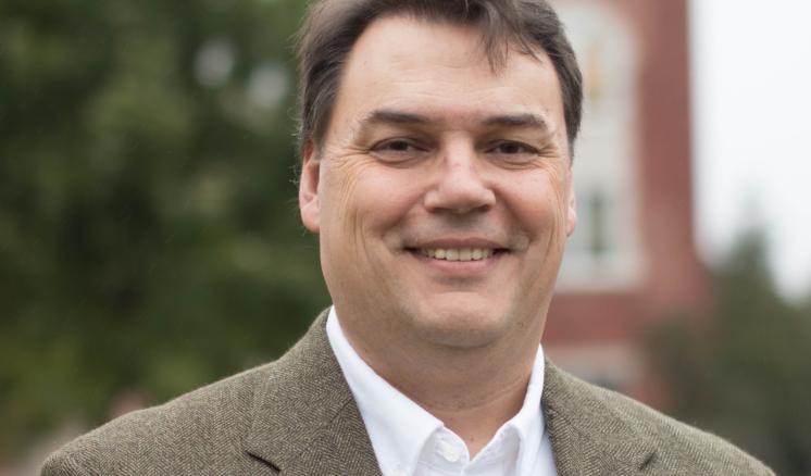 Man smiling at the camera with a building in the background