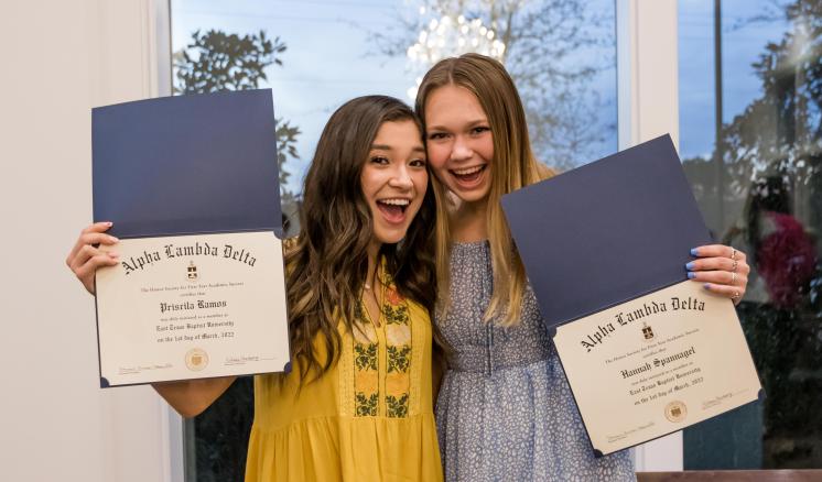 2022_alpha_lambda_delta_honor_society_img_3 Two women smiling at the camera holding up awards in their hands