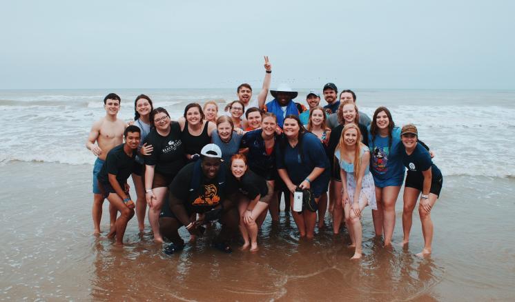 Group of students on the beach smiling at the camera