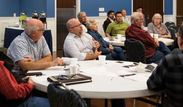 Groups of adults sitting at tables listening to a speaker