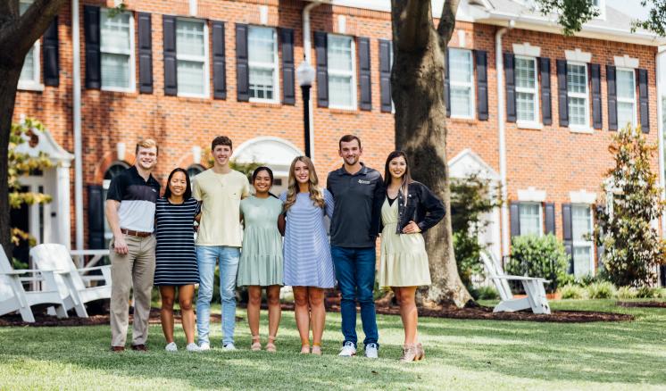 Group of students smiling at the camera in front of a building