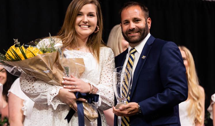 A woman with yellow flowers and a man smiling at the camera