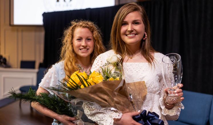Two women with flowers smiling at the camera in chapel