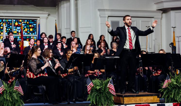 Choir and band singing and playing together with the band professor in front
