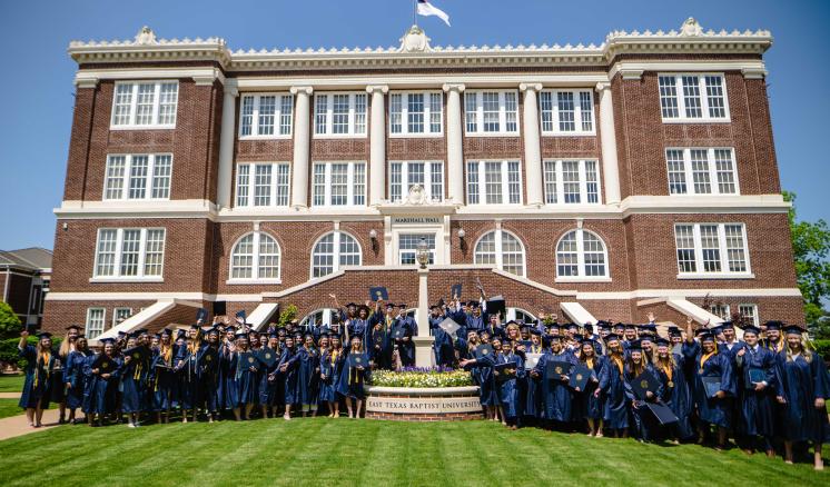 Students in graduation regalia in front of Marshall Hall