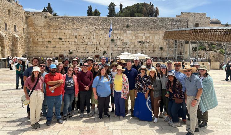 2022_israeltrip_img_1 A group of people smiling at the camera with ruins in the background
