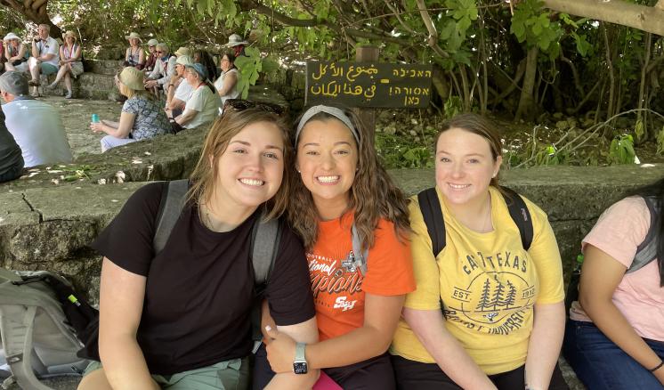 Three females sitting down smiling at the camera 
