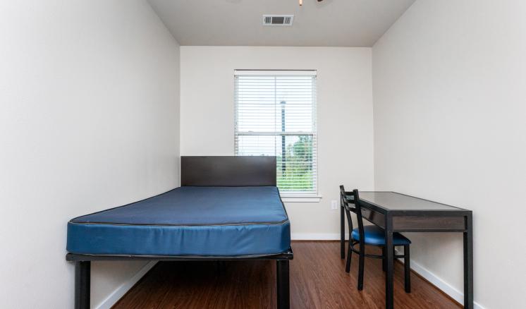 Simple room with a bed, desk, and window.