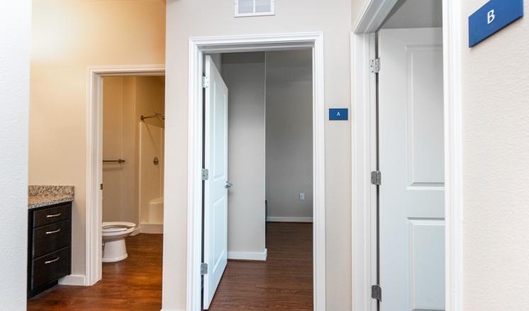 Interior view with a corridor, bathroom, and adjoining room.