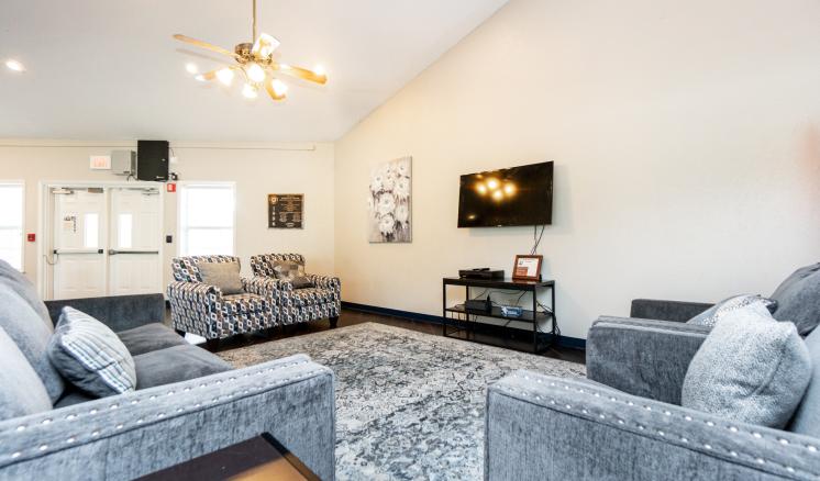 Spacious, modern living room with gray sofas, a mounted TV, and a chandelier.