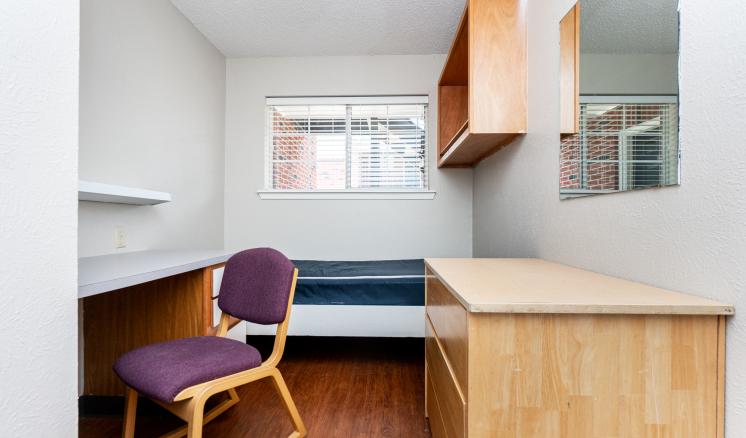Small room with desk, chair, bed, cabinet, and dresser.