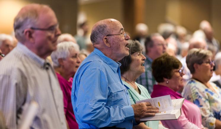 Older men and women singing in a chapel