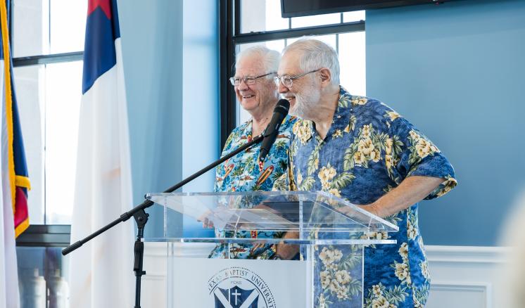 Two men smiling behind a podium