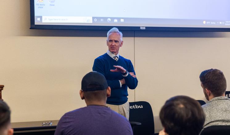 A man talking to a group of people inside