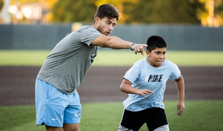 A man pointing in the direction he wants the little boy to run