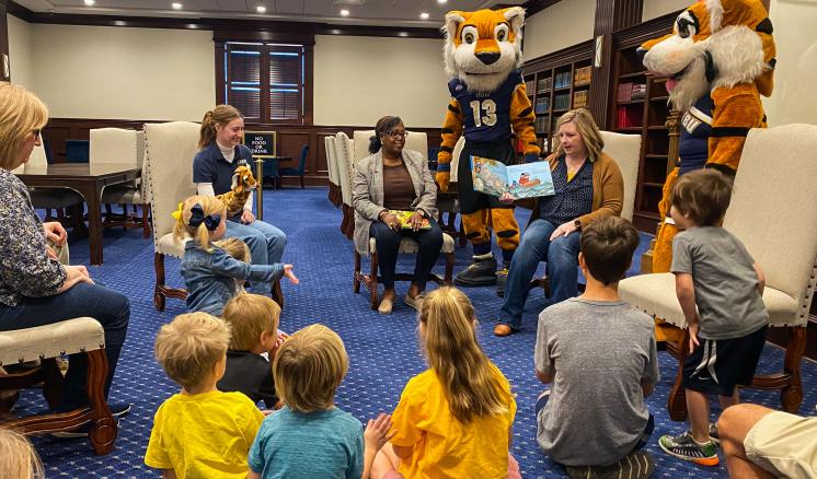 Kids sitting on the floor listening to a story with the tiger mascots