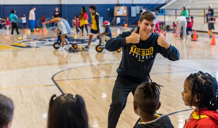 A man giving a thumbs up to a group of little kids in a gym