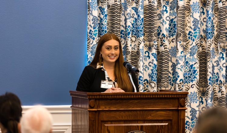 Woman behind a podium looking out at the crowd smiling