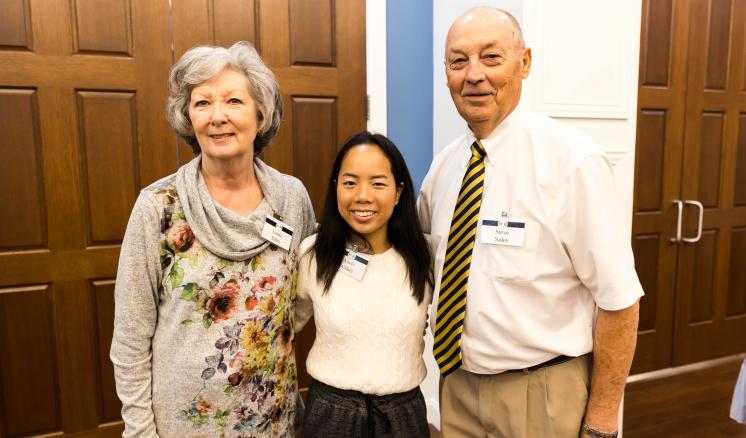 A group of two women and one male smiling at the camera with doors in the background