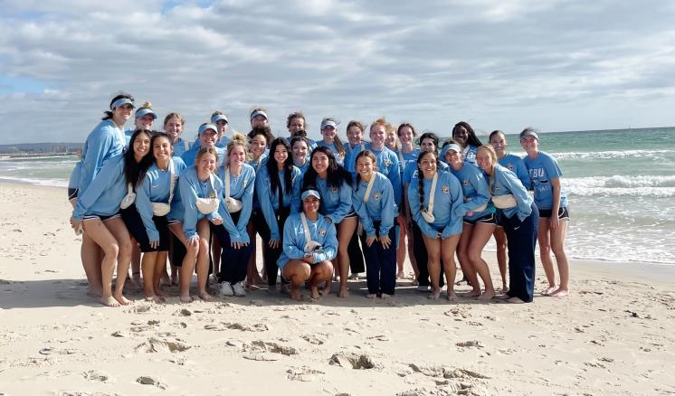 A group of people standing on top of a sandy beach