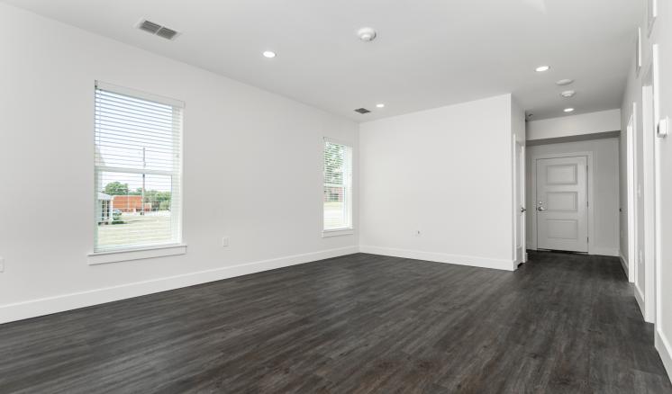 An empty living room with wood floors and white walls