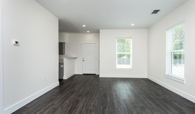 An empty living room with wood floors and white walls