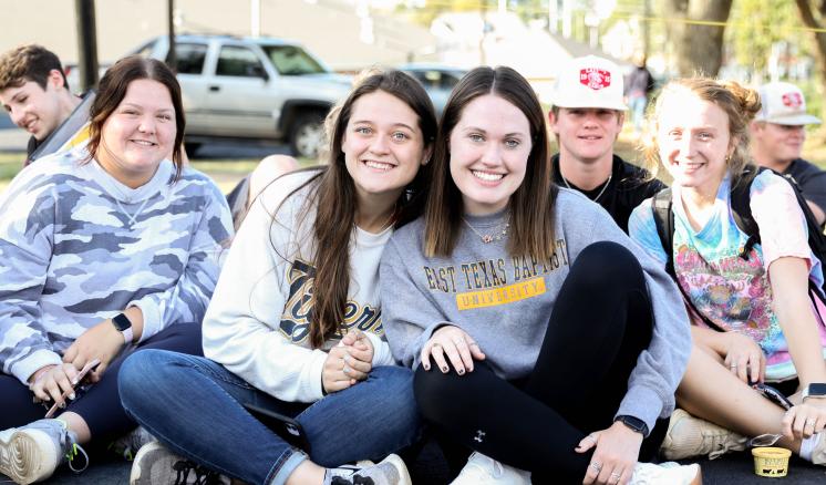 A group of people sitting on the ground posing for a picture