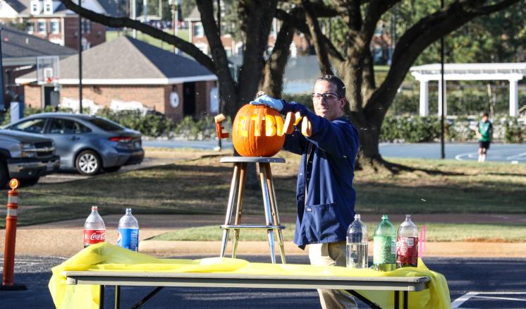A man holding a pumpkin on top of a table