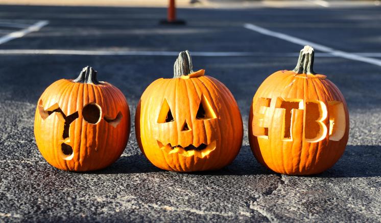 Three carved pumpkins sitting in a parking lot