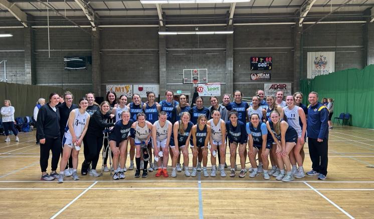 A group photo of two basketball teams and their coaches in a gymnasium.