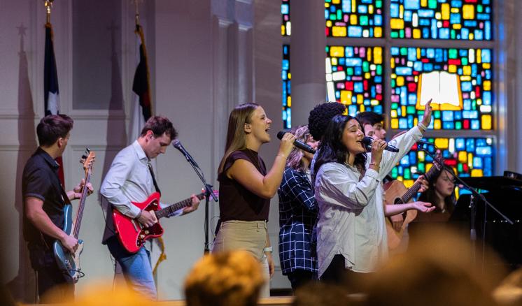 Male and females singing on stage in a chapel