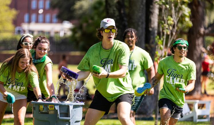 Male and females outside grabbing sponges out of a trash can of water for a game