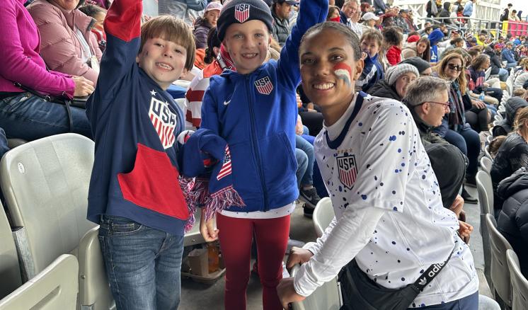 Women poses with two kids in bleachers